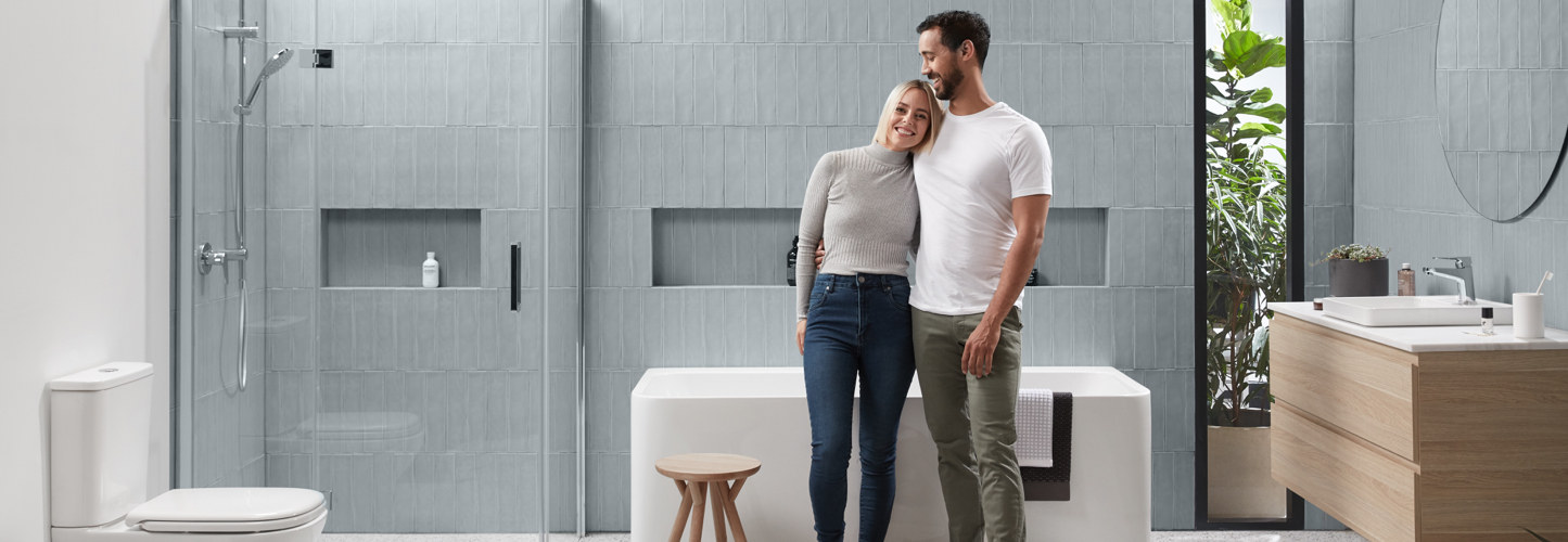 A happy couple stand together in their Domaine bathroom.